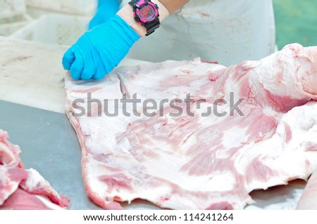 butcher\'s hands cutting pork meat into pieces for a meat market