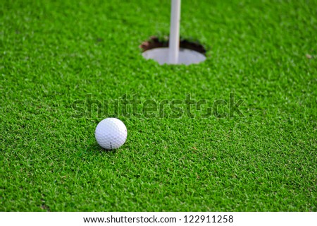 Golf ball and golf hole on the green grass