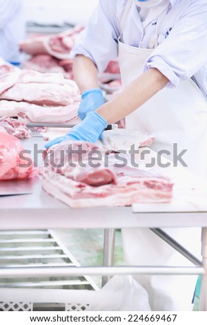 butcher cutting meat on the table in meat industry