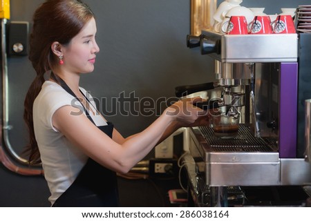Female bartender makes coffee using coffee machine.