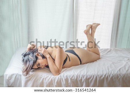 Sexy Asian woman black bikini lying on the bed