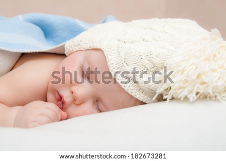 Cute sleeping baby in knitted hat with pompom