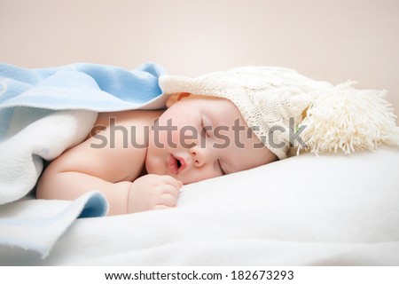 Cute sleeping baby in knitted hat with pompom