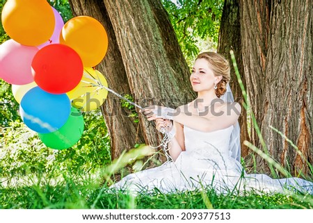 Happy bride holding bunch of colorful balloons