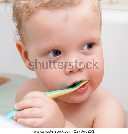 Cute kid brushing teeth in bath