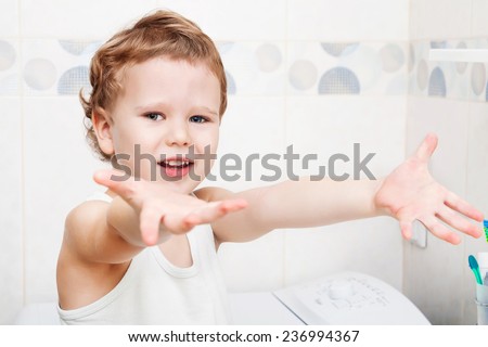 Cute happy kid showing clean hands he washed in bathroom
