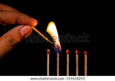 Man hand fire a row of matches on black background