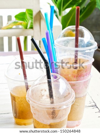 Empty disposable plastic cups with drinking straw on wooden table