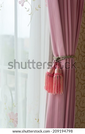 Curtain with curtain tieback at window , selective focus.