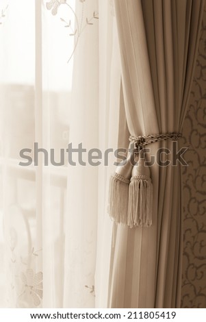 Curtain with curtain tieback at window, selective focus.  Processed with vintage style.