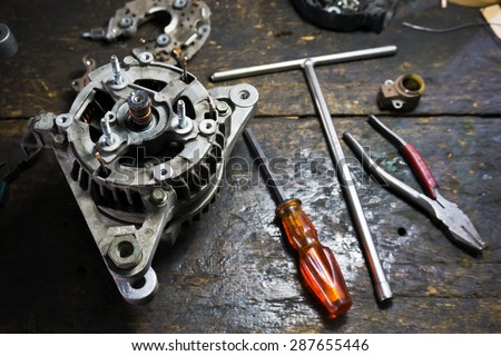 Still life repair of engine parts with Starter car, screwdriver, pliers on old wooden workbench surface.Shallow depth of field.