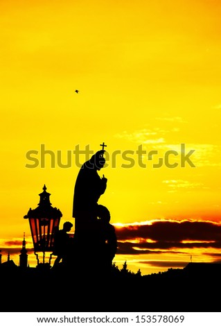 Silhouette of an angel statue from Charles bridge in Prague at sunset.
