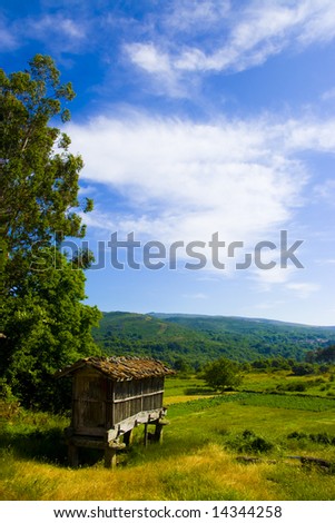 Grain store in an idyllic field with mountains and clouds