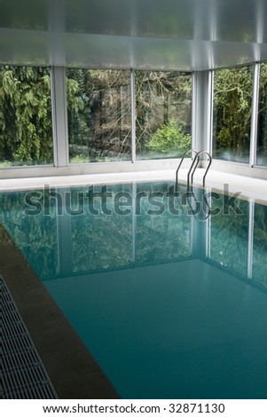 indoor swimming pool surrounded by leafy trees in an idyllic landscape