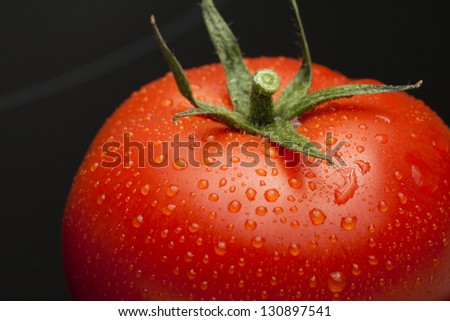 Tomato single with drops isolated on black