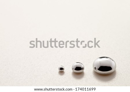 Three mercury drops over a shiny plastic surface