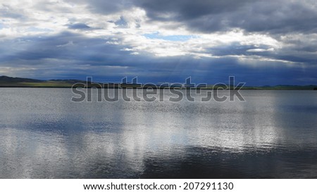 Lake Shira (Khakassia) evening view. Dark cumulus clouds reflecting on the still water surface. Natural landscape, July 17, 2014.