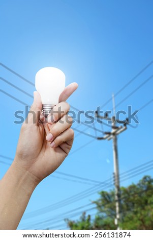 hand with light bulb, electricity pole background