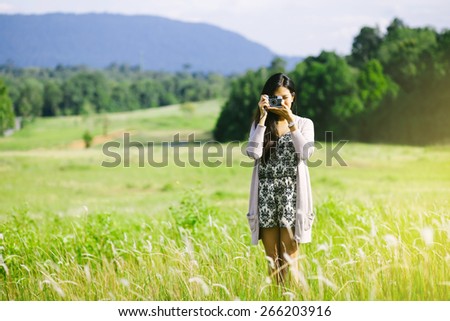 Women taking photo on field with retro camera, nature touch