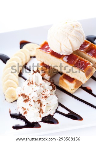 Plate of belgian waffles with ice cream and whipped cream, Strawberry sauce and bananas on white background
