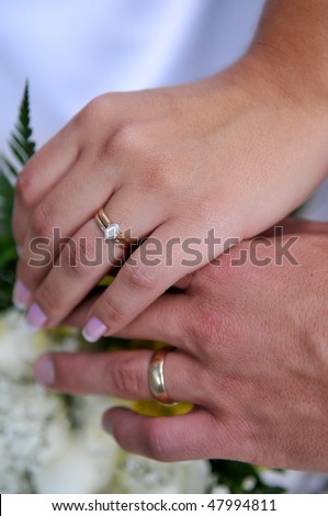 stock photo Bride and groom holding hands with wedding rings over bouquet