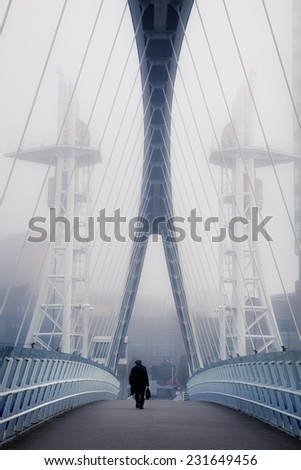 Man crossing the bridge going for a work in a foggy morning.