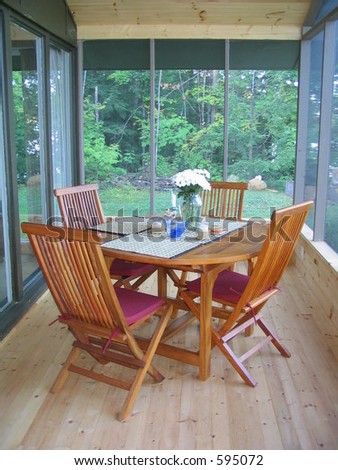 Screened in cottage porch with teak table and chairs set and ready for entertaining