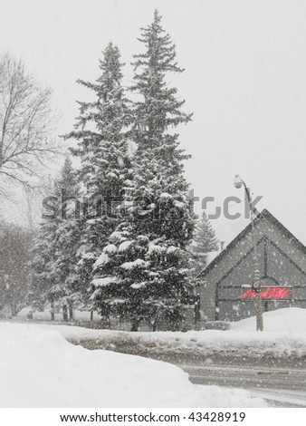 stock photo : gray winters day with evergreen trees snow and a restaurant 