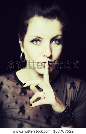 dark portrait of a woman with finger on lips