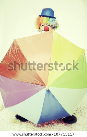 studio shot of a clown with a big umbrella
