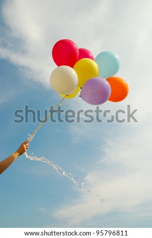 hand holds a bunch of balloons