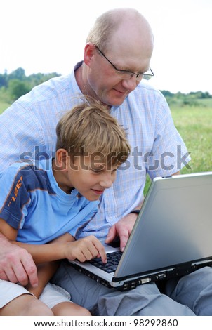 father and son with laptop outdoors