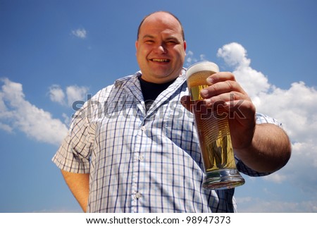 happy man with a glass of beer in front of blue cloudy sky