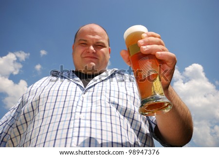 happy man with a glass of beer in front of blue cloudy sky