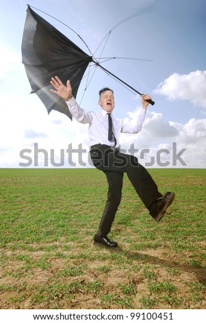 man in business clothing with fights with his umbrella outdoors
