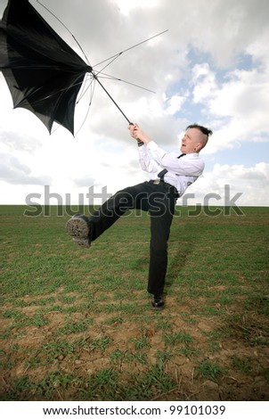 man in business clothing fights with his umbrella outdoors