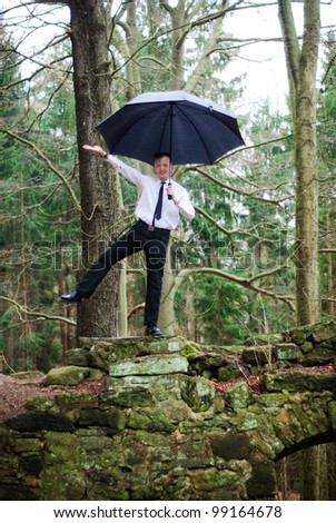 goth guy in business clothes dances with an umbrella