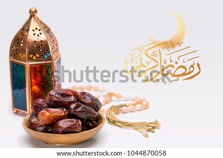Blessed or generous holy month of Ramadan. Ramadan Kareem or Mubarak Arabic Text, close up of oriental Lantern lamp with dates on wooden plate & rosary on white background. Islamic Greeting Card