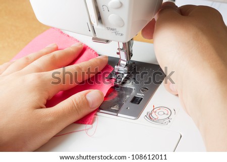 sewing a pink dress on a sewing machine