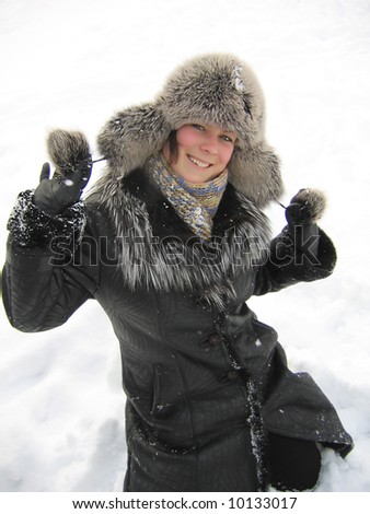 Cheerful girl in fur cap on snow background