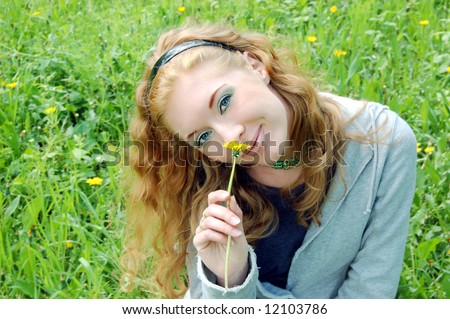 Lovely red-haired girl sniffing dandelion