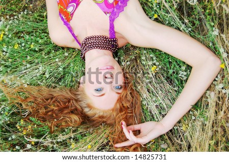 Beautiful girl with flower diadem lying in grass