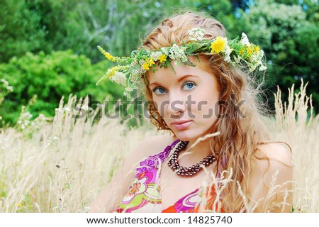 Beautiful girl with flower diadem among fields
