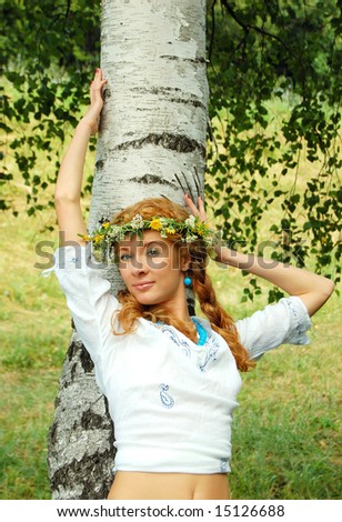beautiful redhead girl with flower diadem near birch