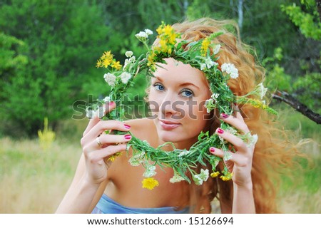 portrait of beautiful sunny redhead girl looking through flower diadem