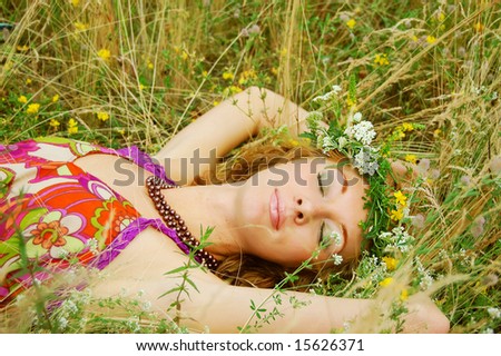 Beautiful girl with flower diadem lying in grass
