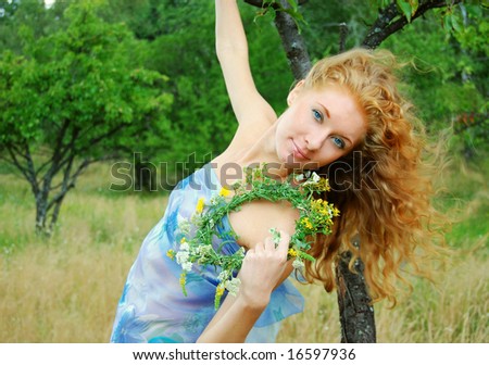 Redhead girl with flower diadem in garden with flying hair