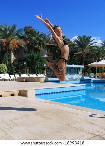 Active slim girl jumping on swimming pool background