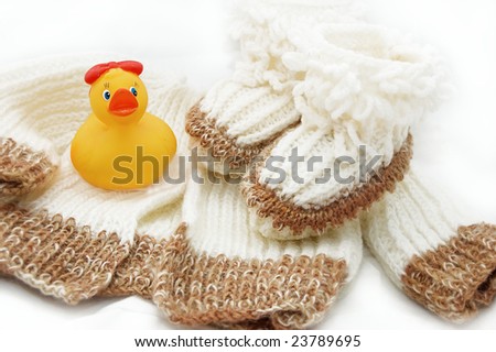 wool hand-made baby coat, socks and toy over white