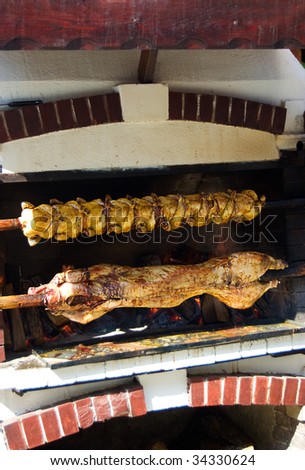 Pig and chicken on a spit grilling